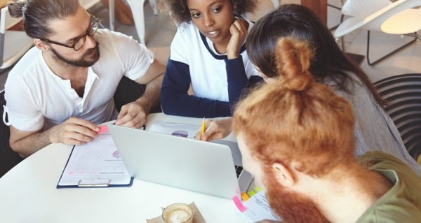 top view of stylish, trendy, hipster looking future marketing specialists working hard on their graduation project, brainstorming ideas of successful start up, developing plan of promising business